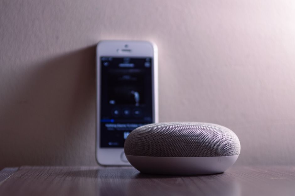 Smartphone met Google Home app naast een smart speaker tijdens het instellen van een apparaat