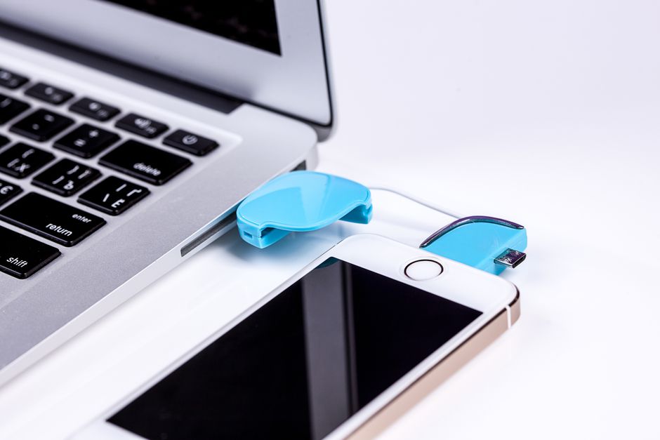 Smartphone met USB-kabel aangesloten op een laptop om foto's over te zetten