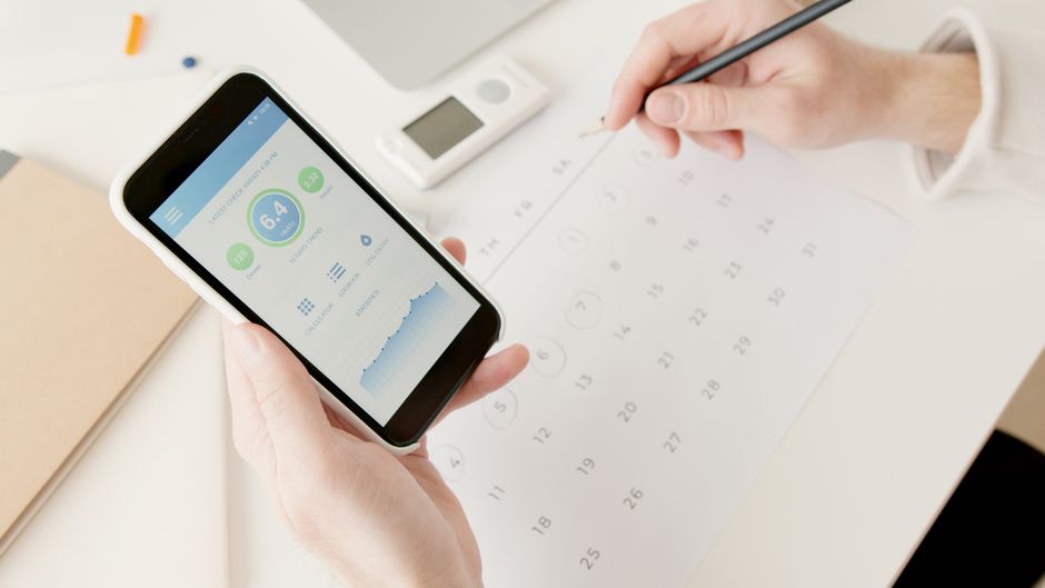 Hand met smartphone die een datum kiest via een WhatsApp-peiling